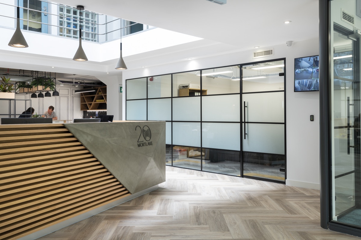 Eye-Catching Office Entrances -Glenstone Property - Bright, open lobby with herringbone wood flooring and frosted glass partitions