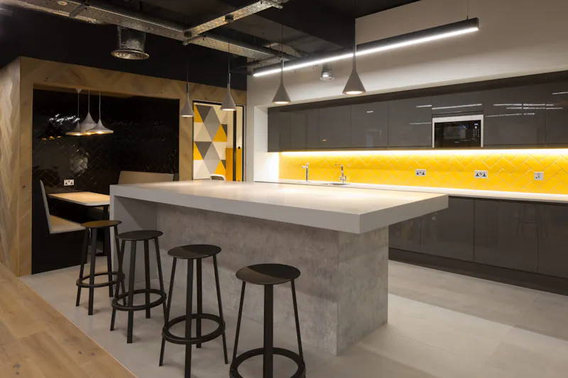 Social Kitchen and Kitchenette — DTRE, Coin Street by K2 Space Office kitchen with concrete island, bar stool seating and banquette at DTRE Coin Street by K2 Space